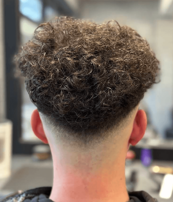 Curly texture on top with a smooth skin fade and clean neckline